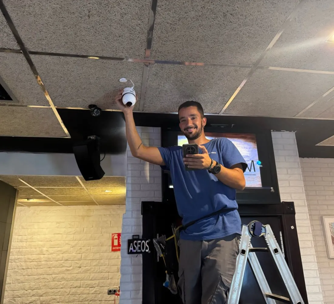 Técnico instalando una cámara de seguridad en el techo de un local